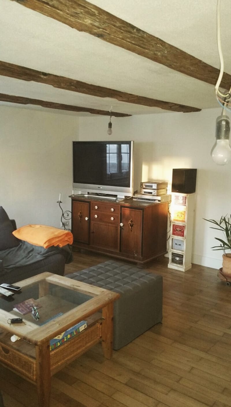 Sanierter Wohnraum im Altbau mit freigelegten Holzbalken an der Decke
