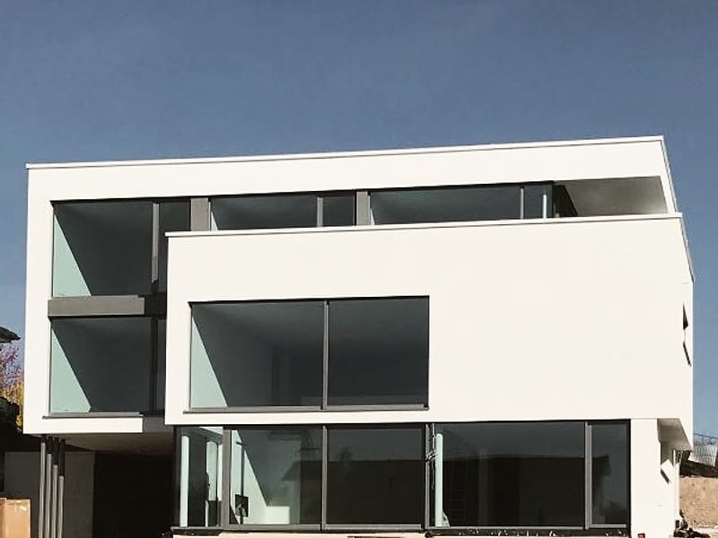 Neubau mit weiß verputzter Fassade aus versetzten Kuben und großen Glasflächen
